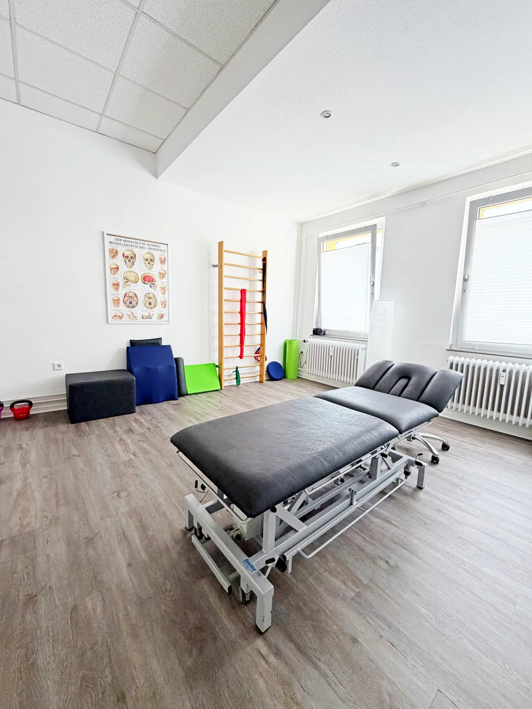 Behandlungsraum mit Therapieliege, Sprossenwand und Trainingsgeräten für Krankengymnastik