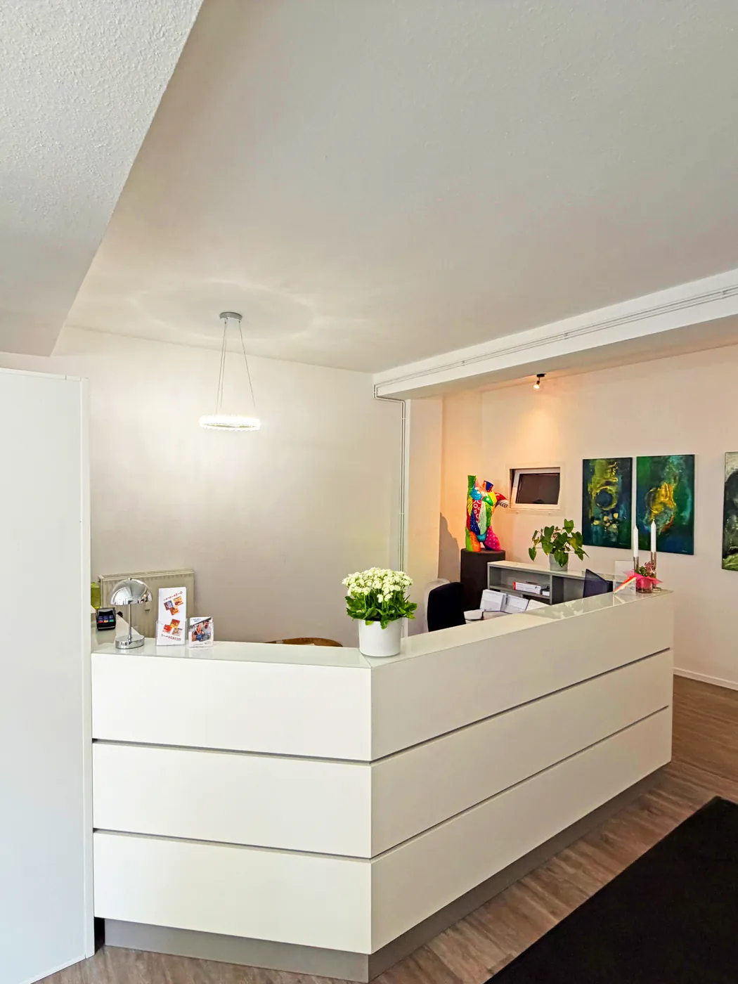 Empfangstresen der Physiotherapie Lichtblick.life in Hagen mit Blumen und Kunst an den Wänden